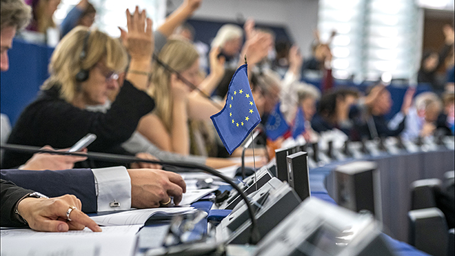 Auditorium with raised hands and EU flag 